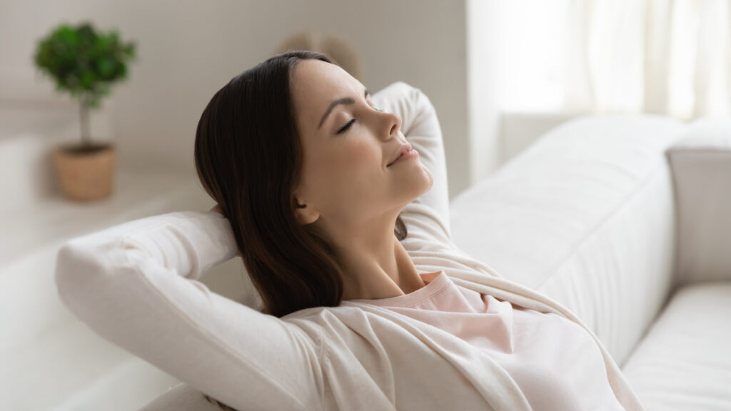 woman relaxing in home breathing clean air from air purifier